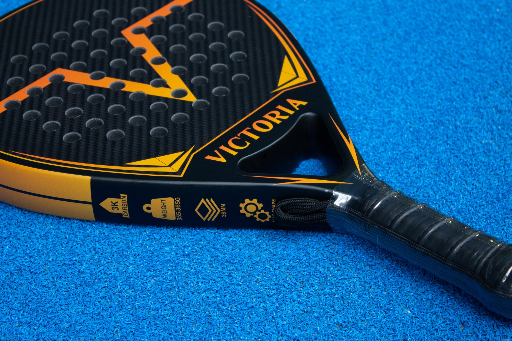 victoria padel druppel tear racket 3k carbon zwart oranje productfoto blauwe achtergrond zijkant closeup