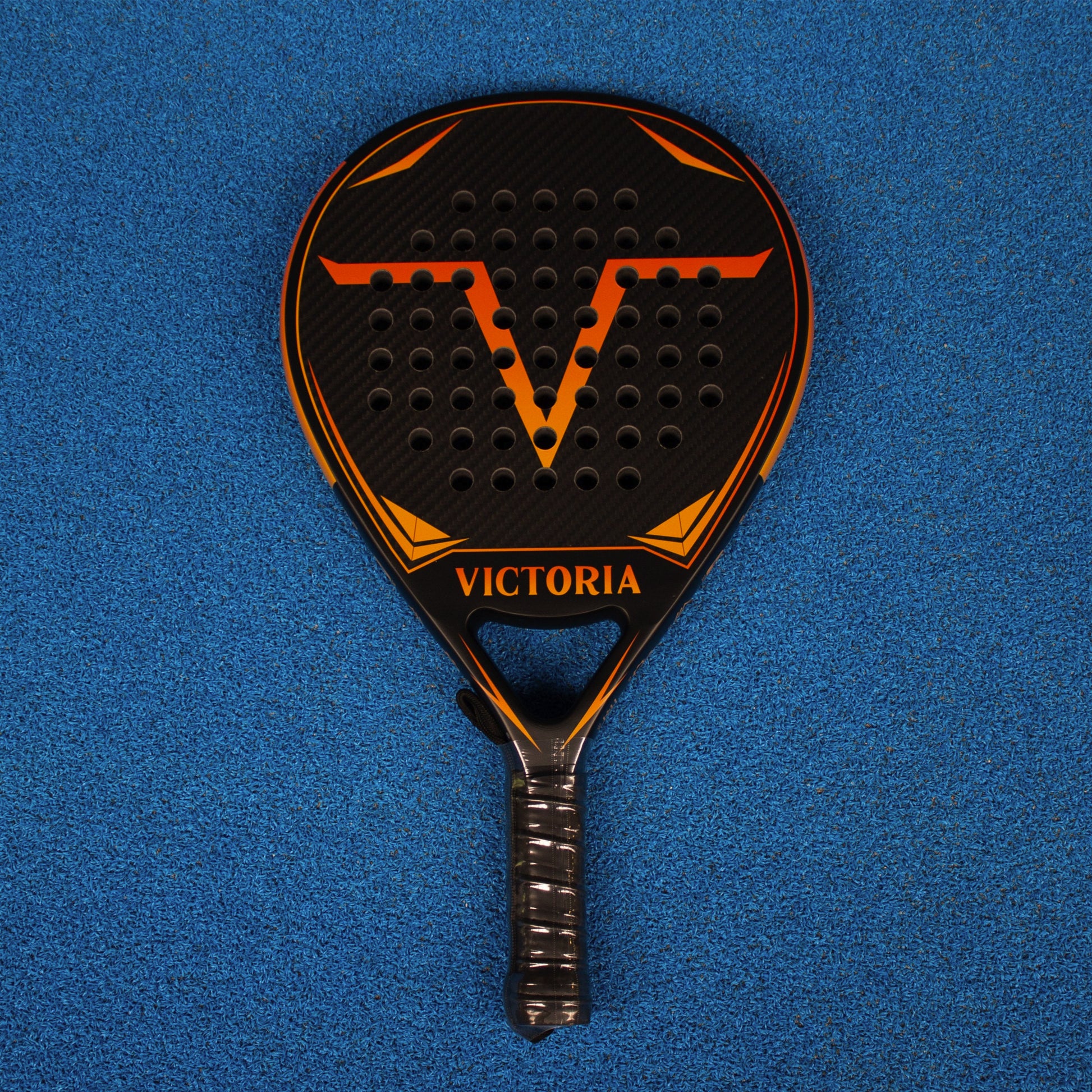 victoria padel tear druppel racket 3k carbon zwart oranje productfoto blauwe achtergrond 4